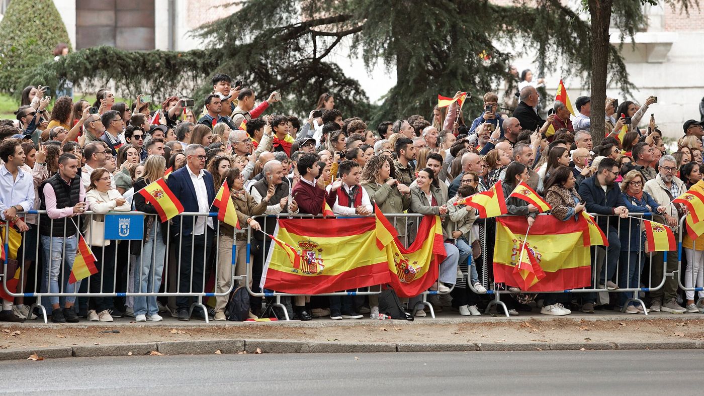 Público tras las vallas del desfile, con banderas de España colgadas y en la mano