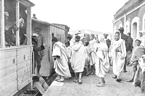 Hombres con chilaba junto a un vagón de tren en la estación de Segangan