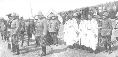 Militares con salacot y notables rifeños junto a la vía del tren
