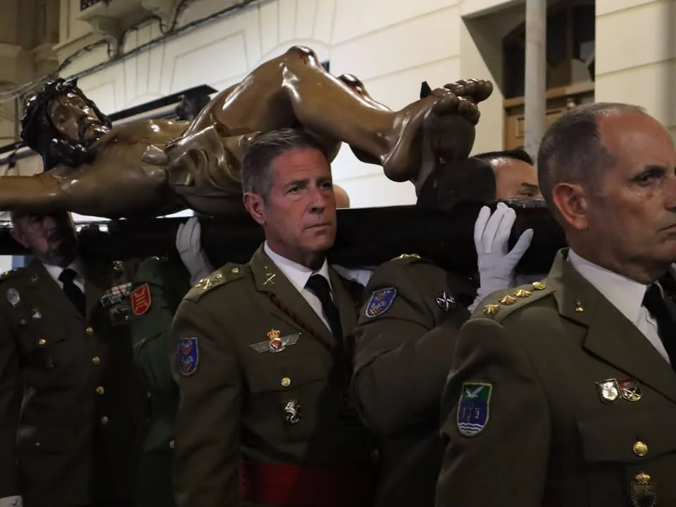 Militares del Ejército de Tierra con uniforme de gala portan a hombros un crucificado en una procesión de Semana Santa en Melilla