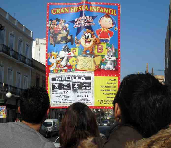 Padres melillenses interesándose por la cartelería del espectáculo colocada en el centro de la ciuda