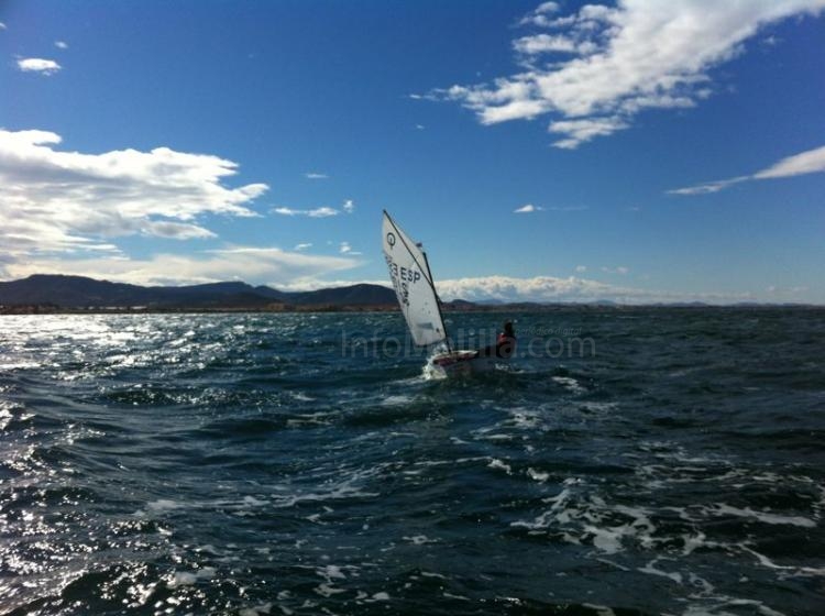 Un "optimist" navegando solitario con las montañas como fondo