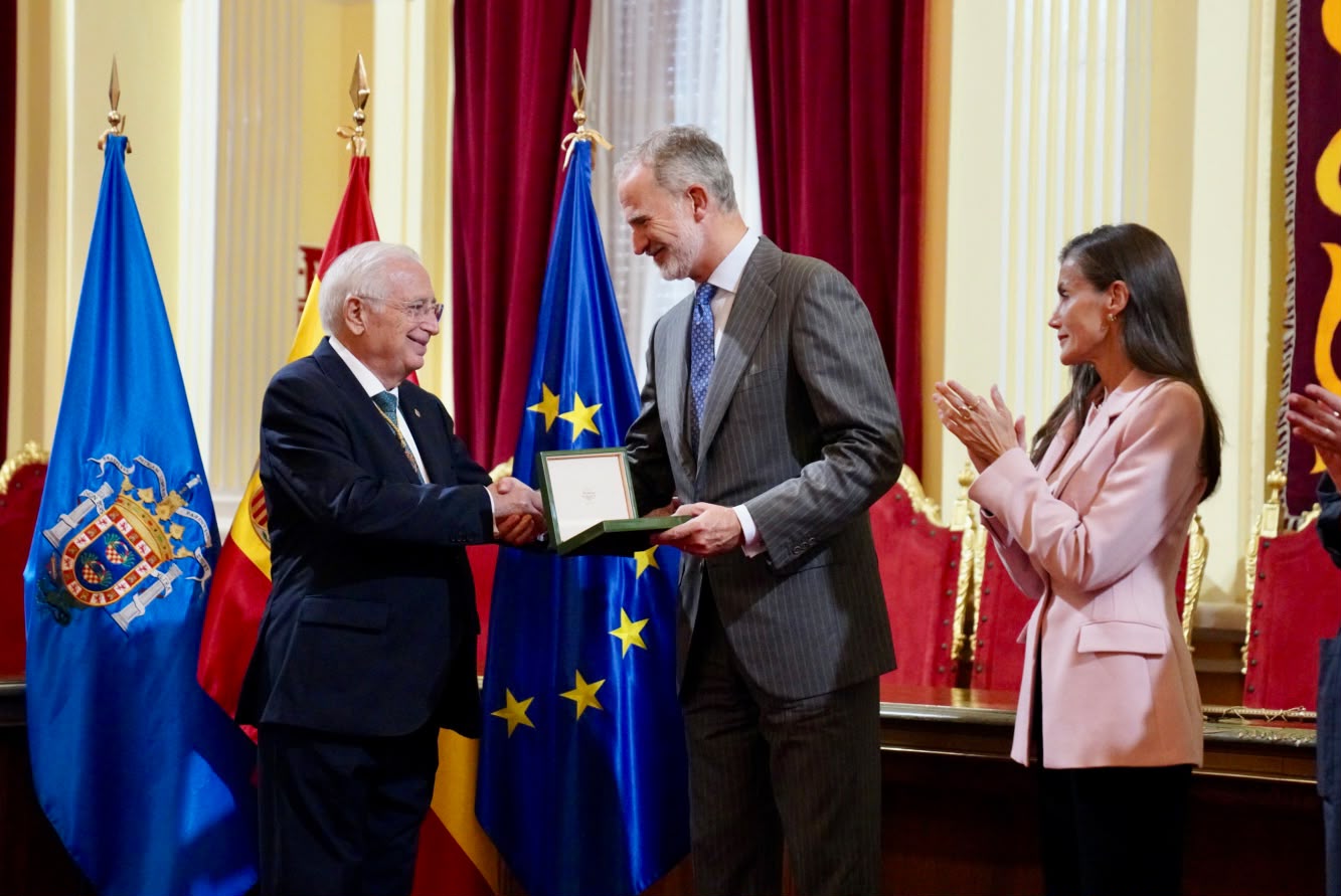 Juan José Imbroda entrega a Felipe VI el estuche con las Llaves de la Ciudad mientras doña Letizia aplaude, con las banderas de Melilla, España y Europa al fondo.