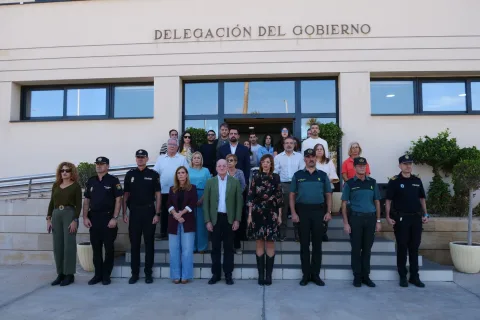 Un grupo de personas, algunas con uniforme policial, posa en las escaleras de la entrada de un edificio oficial.